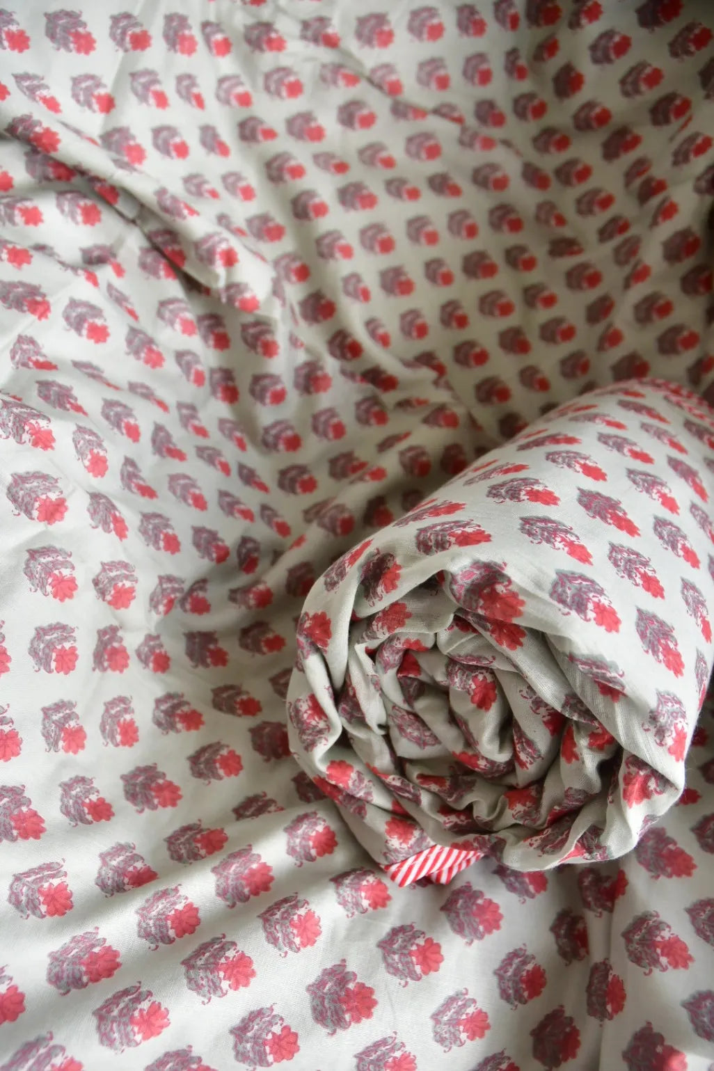 Roll of fabric with red floral pattern on a matching fabric background