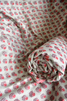 Roll of fabric with red floral pattern on a matching fabric background
