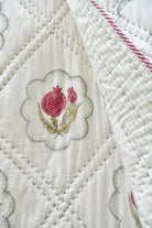 Close-up of a quilt with floral embroidery on a white background