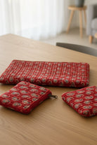 Three red patterned pouches on a floral fabric background