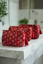 Red patterned toiletry bags on a marble surface with a blurred bathroom background