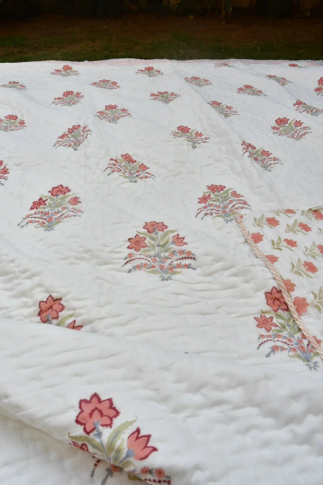 Floral patterned quilt on a bed with a dark background