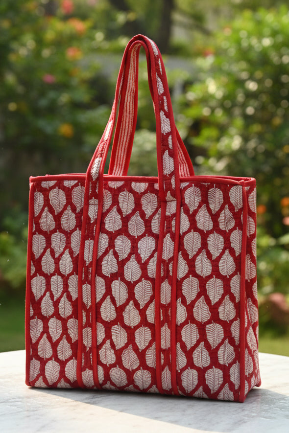 Red patterned bag on a surface with a floral-patterned fabric background