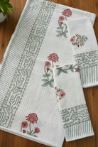 Set of white towels with floral and geometric patterns on a wooden surface