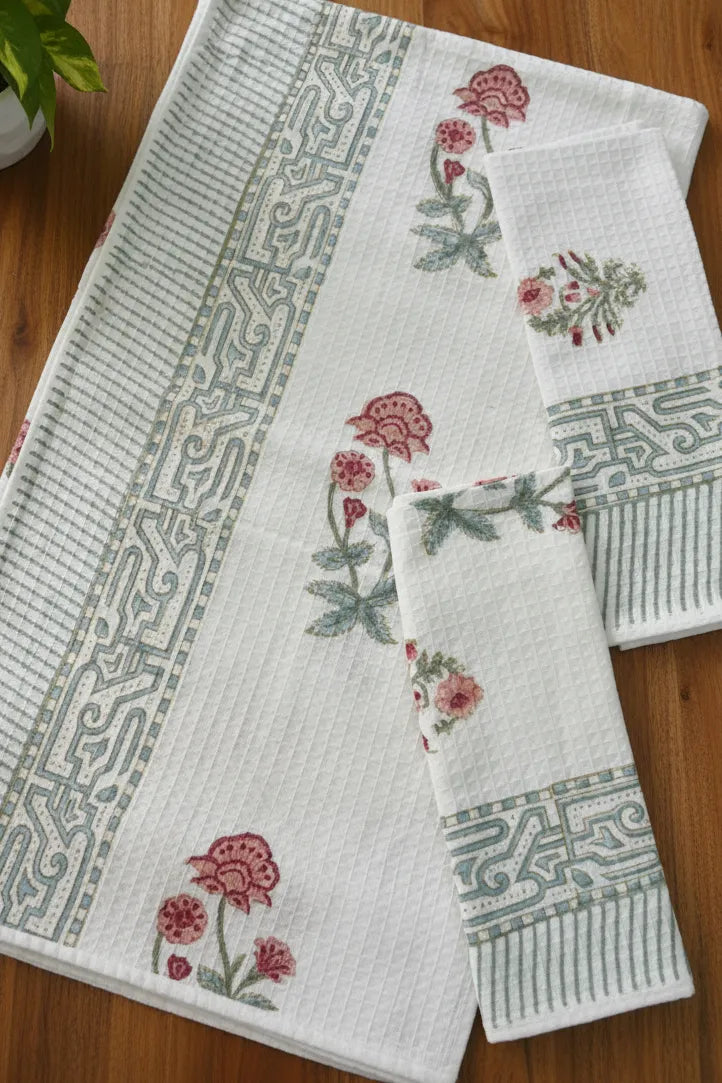 Set of white towels with floral and geometric patterns on a wooden surface