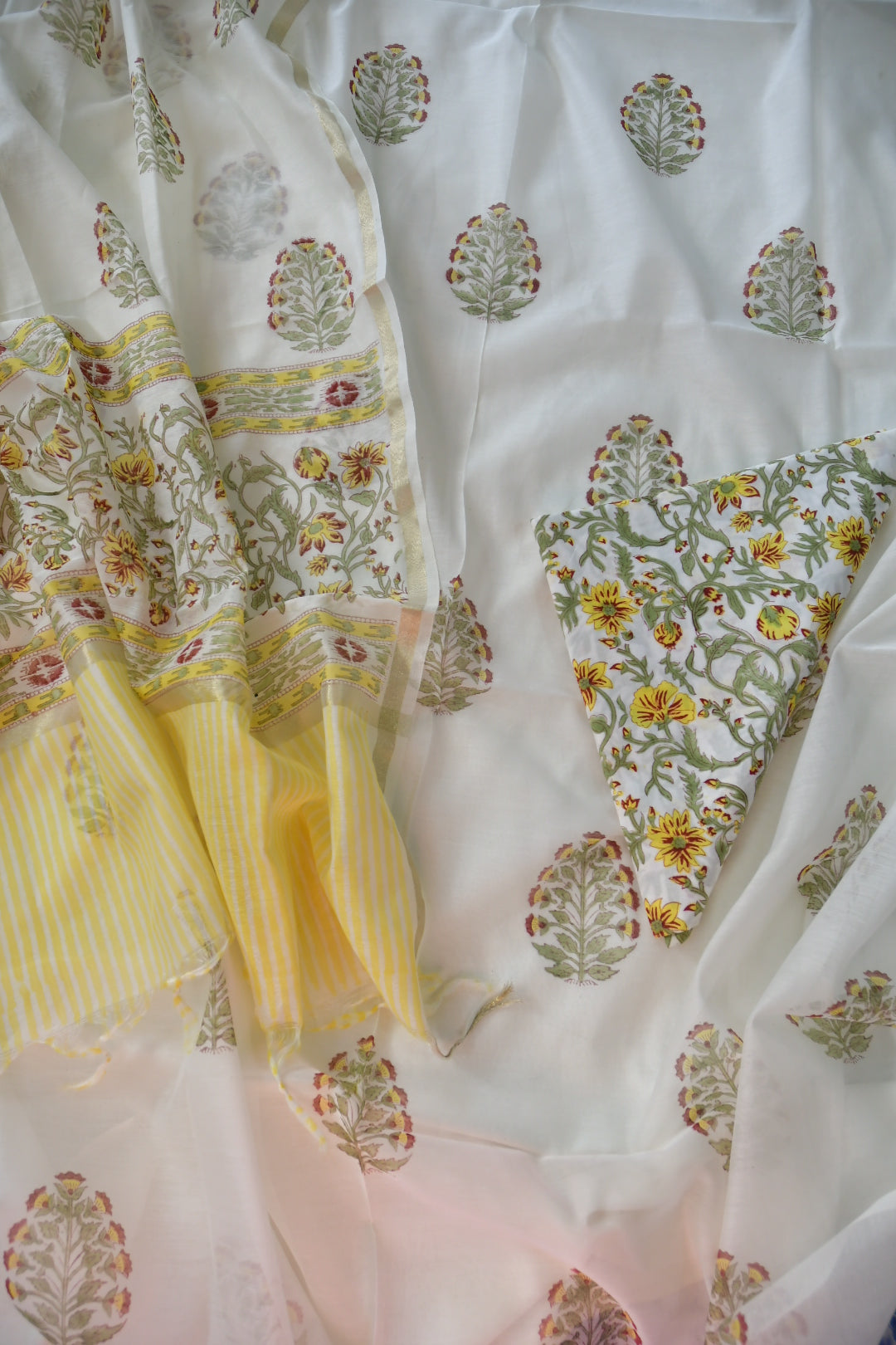 Close-up of a fabric with floral and geometric patterns in white, yellow, and green.