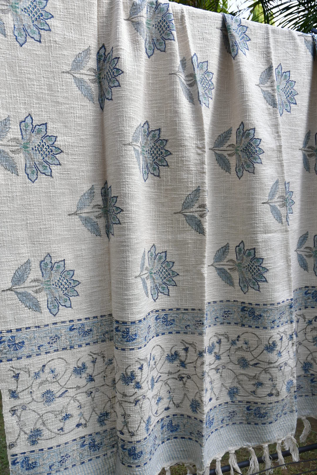 White throw with blue floral patterns, possibly a sari or fabric swatch.