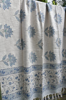 White throw with blue floral patterns, possibly a sari or fabric swatch.
