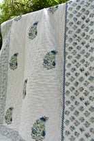 White quilt with blue floral patterns hanging outdoors
