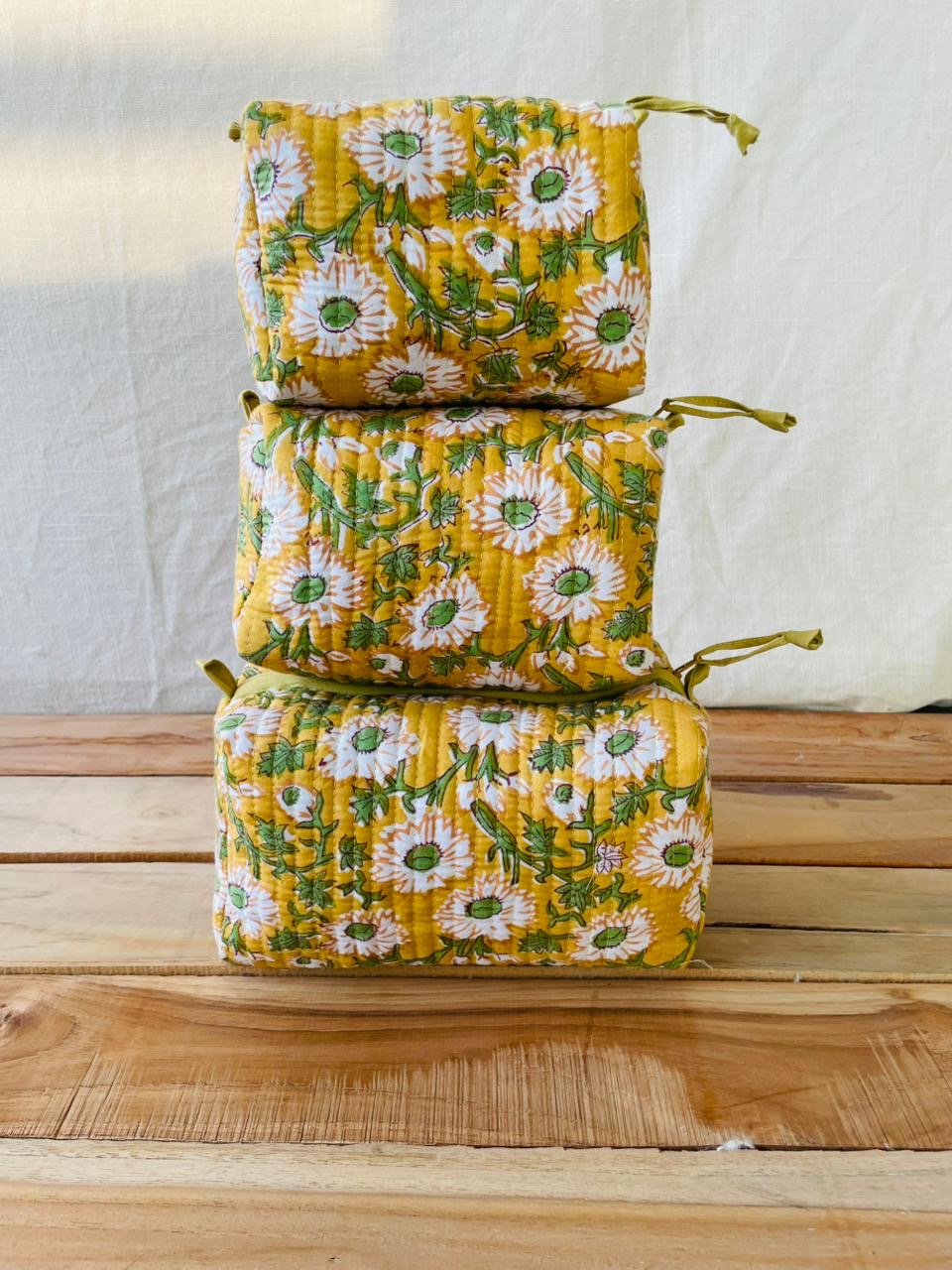 Stack of yellow floral fabric bags on a wooden surface with a white background
