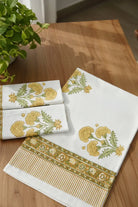 Set of embroidered towels on a wooden table with a plant in the background