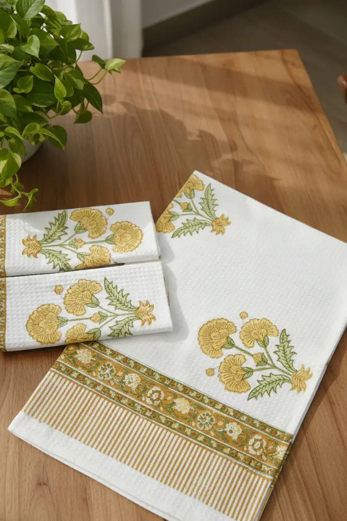Set of embroidered towels on a wooden table with a plant in the background