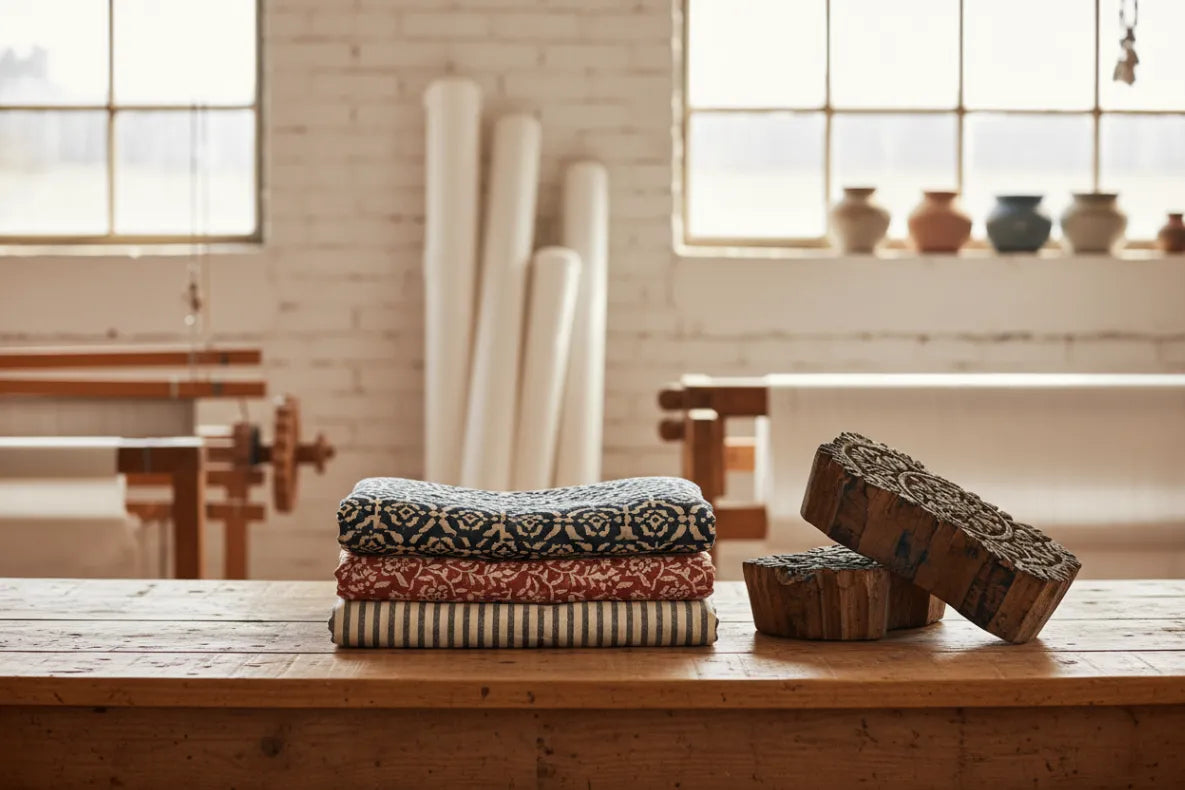 Stack of patterned cloths on a wooden table with a rustic background