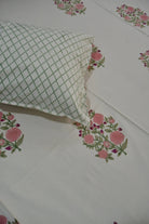 Floral patterned bedsheet with a green checkered pillow on a white background