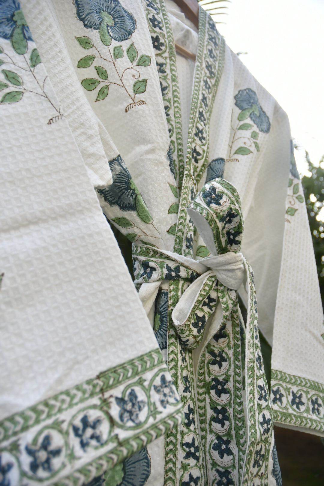 Floral patterned fabric with green and blue designs on a white background