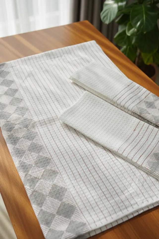 Gray textured cotton towel on a wooden table with a plant in the background