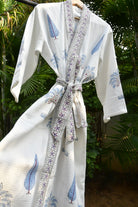 White robe with blue bird pattern and decorative ribbon against a blurred green background