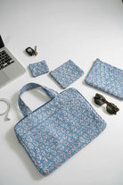 Blue floral laptop bag with smaller bags and accessories on a white surface