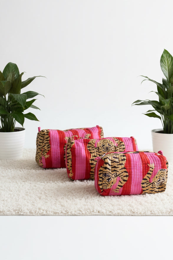 Pink and gold patterned bags hanging on a white textured surface